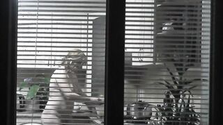 Peeping. Voyeur. Neighbors pervert voyeur inside evening on street looks out window as nude beauty neighbors inside kitchen prepares dinner for her hubby. Nude into outdoor. Nude at home. Family. Public