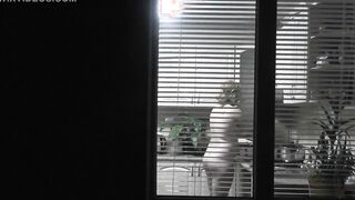 Peeping. Voyeur. Neighbors pervert voyeur inside evening on street looks out window as nude beauty neighbors inside kitchen prepares dinner for her hubby. Nude into outdoor. Nude at home. Family. Public