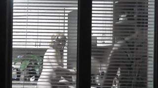 Peeping. Voyeur. Neighbors pervert voyeur inside evening on street looks out window as nude beauty neighbors inside kitchen prepares dinner for her hubby. Nude into outdoor. Nude at home. Family. Public