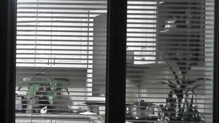 Peeping. Voyeur. Neighbors pervert voyeur inside evening on street looks out window as nude beauty neighbors inside kitchen prepares dinner for her hubby. Nude into outdoor. Nude at home. Family. Public