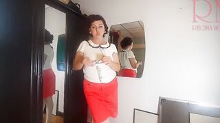 A nude lady does make-up into front of a mirror, slips on panties, tights, a skirt.