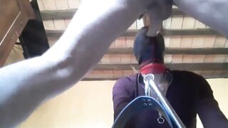 Bound to a machine, masked and hooded, she has to suck a long penis