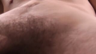 Handsome young man with glasses strokes his hairy cock