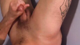 Inked man is stroking his large cock and empties his balls