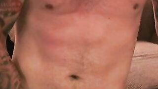Tattooed dude tugging on his cock until he cums on his belly
