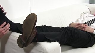 Handsome guy in a suit enjoys feet massage and toe sucking