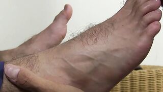 Hunk sits in leather chair while another dude sucks his toes