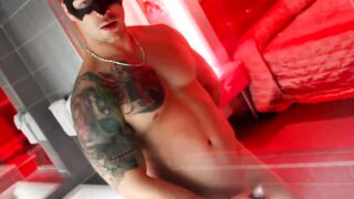 Tattooed athletic man with mask strokes his enormous dick