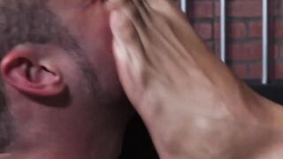 Bearded guard Rikk York receives foot licking from prisoner