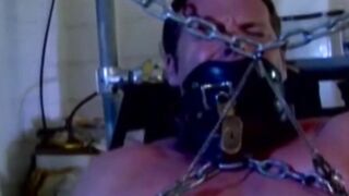 MuscleJockBound.com - Muscular man silenced with a ball gag while being heavily chain