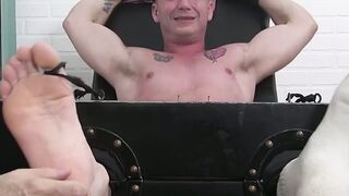 Inked young man has his feet and toes tickled by his friend