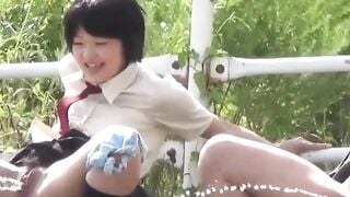 Two uniformed schoolgirls relieve themselves in the grass