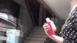 Cameraman hands her juice bottle as she seeks a spot to pee