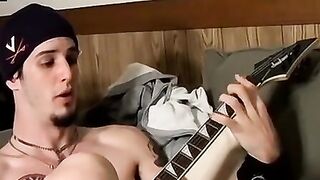 Guitar player strums while stroking hairy cock