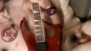 Guitar player strums while stroking hairy cock