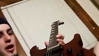 Guitar player strums while stroking hairy cock