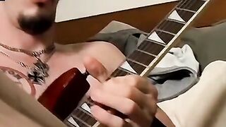 Guitar player strums while stroking hairy cock