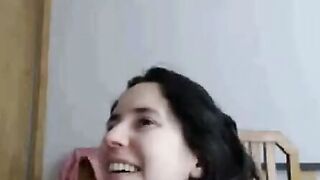 Brunette with Dark Hair Bends Over Bed in Bedroom Scene