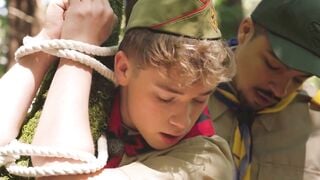Scout boy bound up against a tree inside the woods by 2 mature scout boys